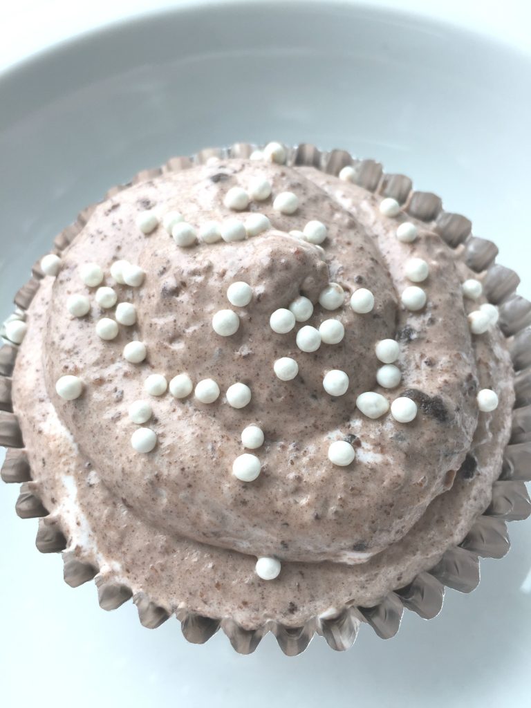 close up of grey stuff dessert in a foil cupcake tin, topped with white sprinkels