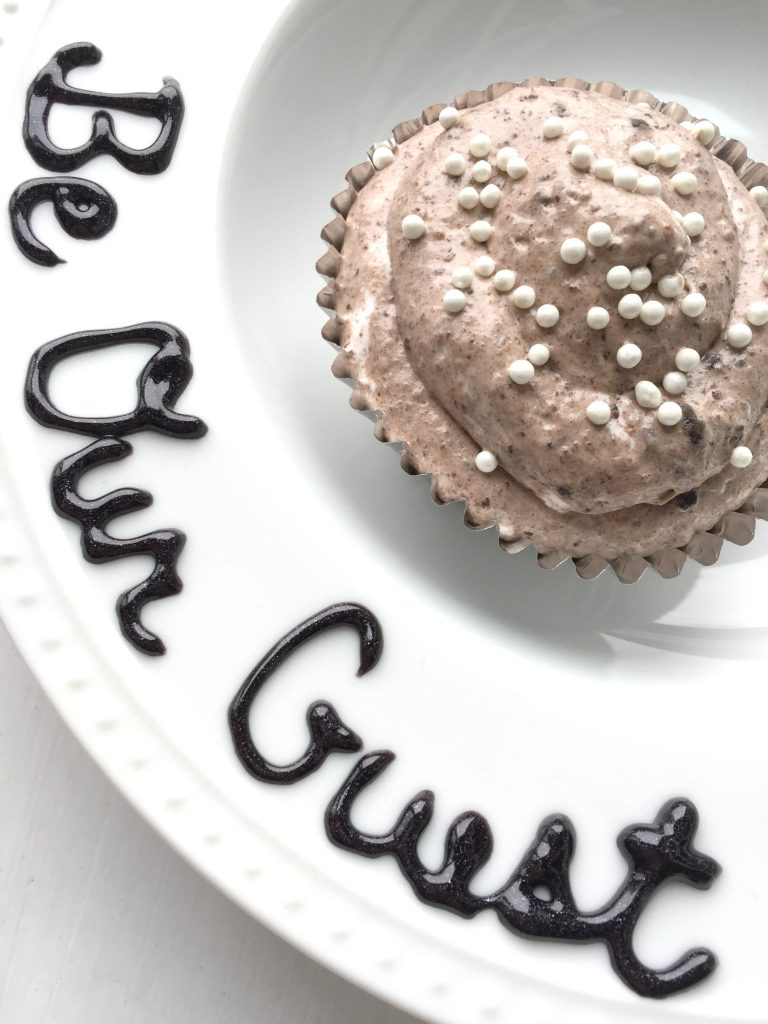 "Be our guest" written on a plate that is holding grey stuff dessert